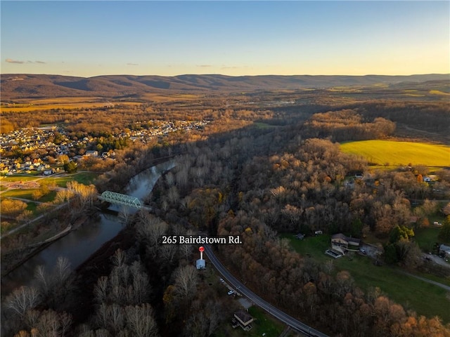 aerial view at dusk featuring a water and mountain view