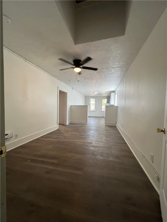 spare room with baseboards, a textured ceiling, dark wood-style floors, and a ceiling fan