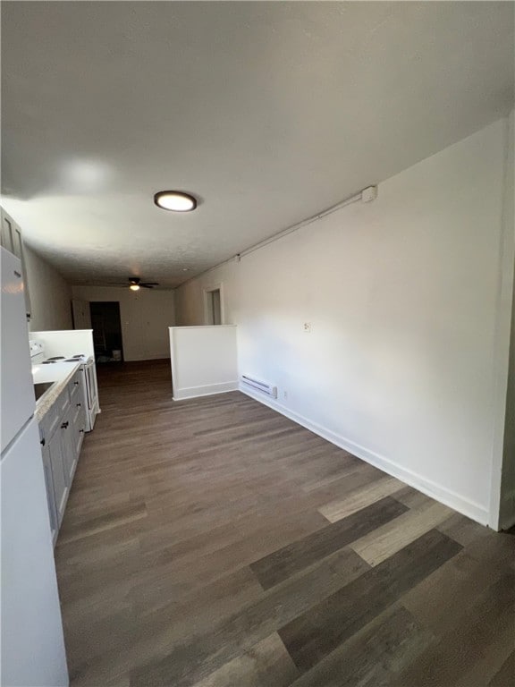 kitchen featuring dark wood-type flooring, open floor plan, freestanding refrigerator, light countertops, and baseboards