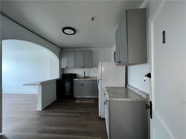 kitchen featuring dark wood-type flooring, black range with electric stovetop, gray cabinets, a sink, and light countertops