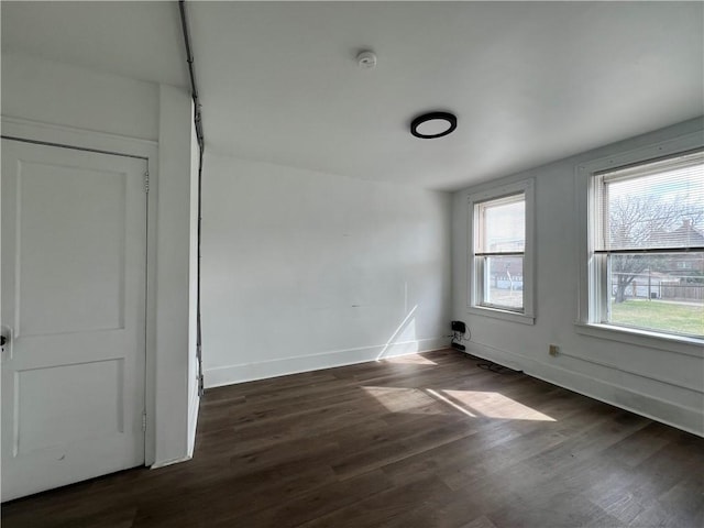 spare room with dark wood finished floors and baseboards