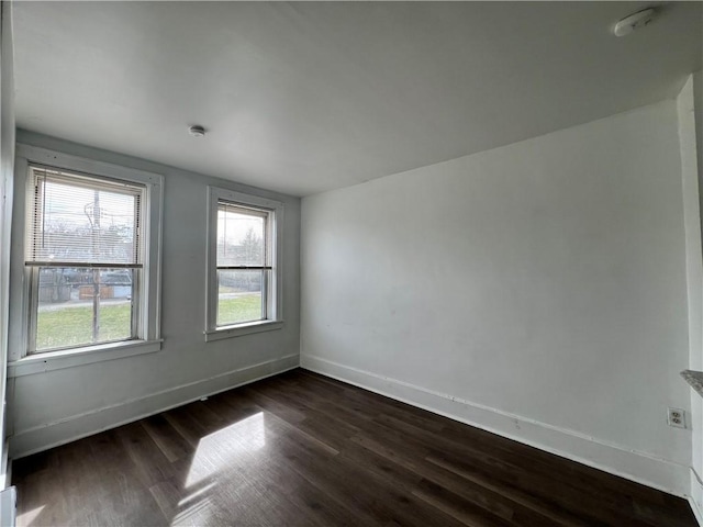 empty room with dark wood-type flooring and baseboards