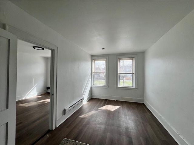 unfurnished room featuring dark wood-style floors, a baseboard heating unit, and baseboards