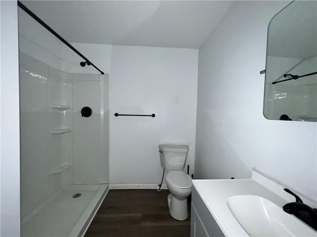 bathroom featuring toilet, walk in shower, wood finished floors, and vanity