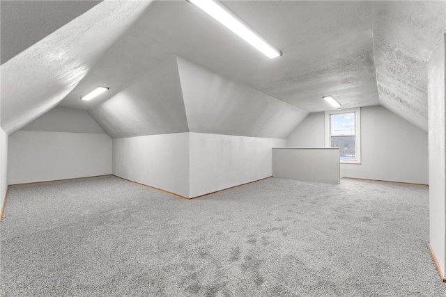 bonus room with a textured ceiling, carpet floors, and lofted ceiling