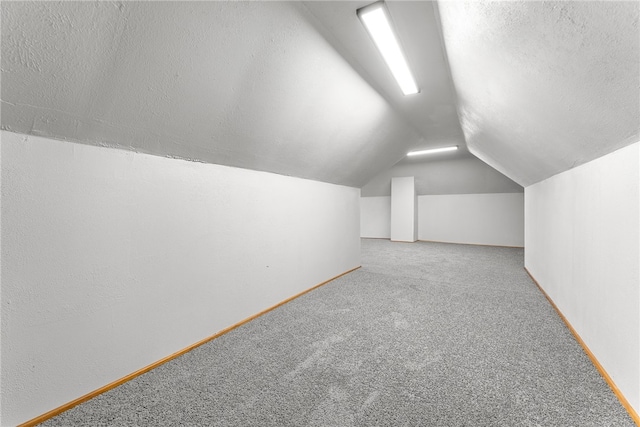 bonus room featuring a textured ceiling, light colored carpet, and vaulted ceiling