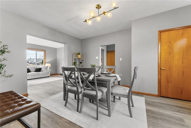 dining room with light hardwood / wood-style floors and a notable chandelier