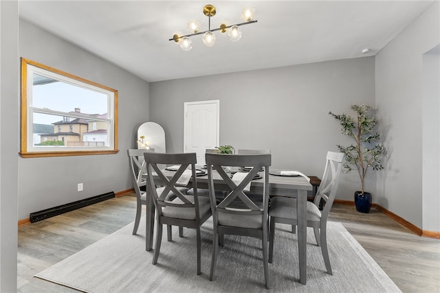 dining area featuring a baseboard radiator, a notable chandelier, and light wood-type flooring