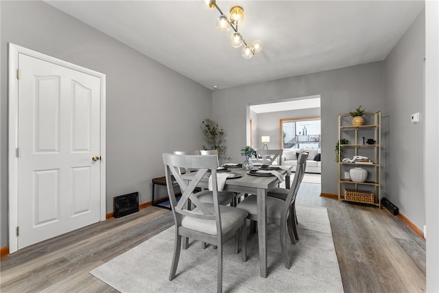 dining area with hardwood / wood-style floors and a notable chandelier