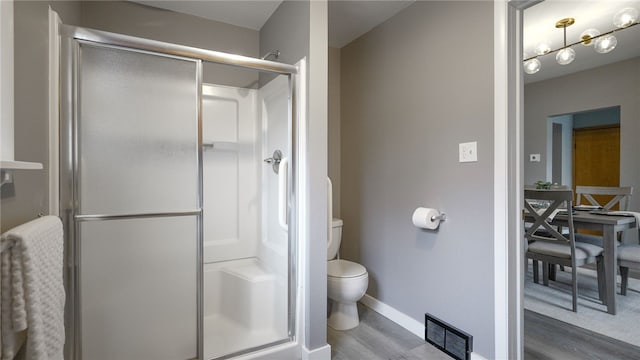 bathroom with hardwood / wood-style flooring, toilet, and a shower with shower door