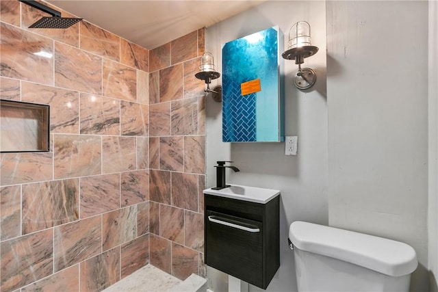 bathroom with tiled shower, vanity, and toilet