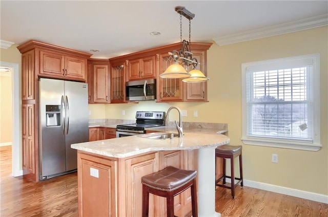 kitchen with a kitchen breakfast bar, ornamental molding, appliances with stainless steel finishes, decorative light fixtures, and kitchen peninsula