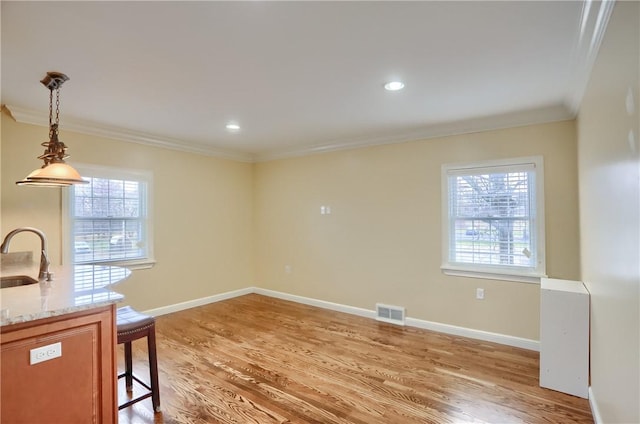 unfurnished dining area with hardwood / wood-style flooring, crown molding, and sink