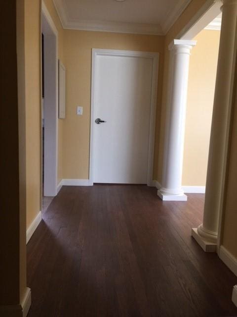 corridor with ornate columns, dark hardwood / wood-style floors, and ornamental molding