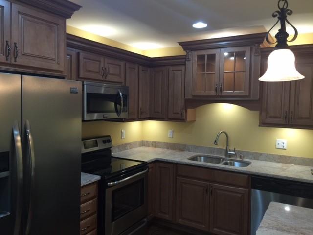 kitchen with appliances with stainless steel finishes, decorative light fixtures, light stone counters, and sink