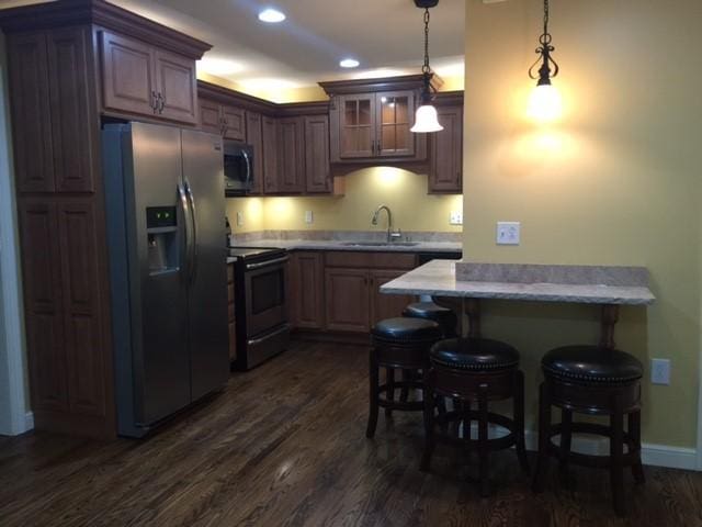 kitchen with a breakfast bar, sink, range with electric stovetop, dark hardwood / wood-style flooring, and stainless steel fridge with ice dispenser