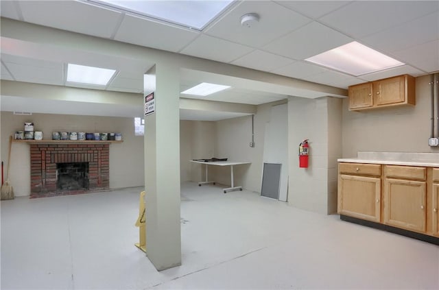 basement with a paneled ceiling and a brick fireplace