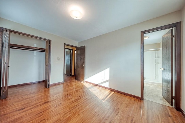 unfurnished bedroom featuring a closet, connected bathroom, and light hardwood / wood-style flooring