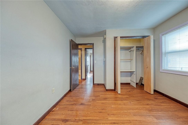 unfurnished bedroom with a closet, a textured ceiling, and light wood-type flooring