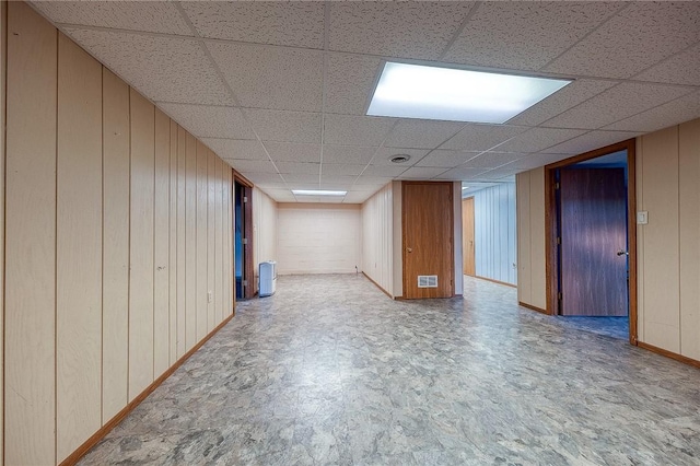 basement with a paneled ceiling and wooden walls