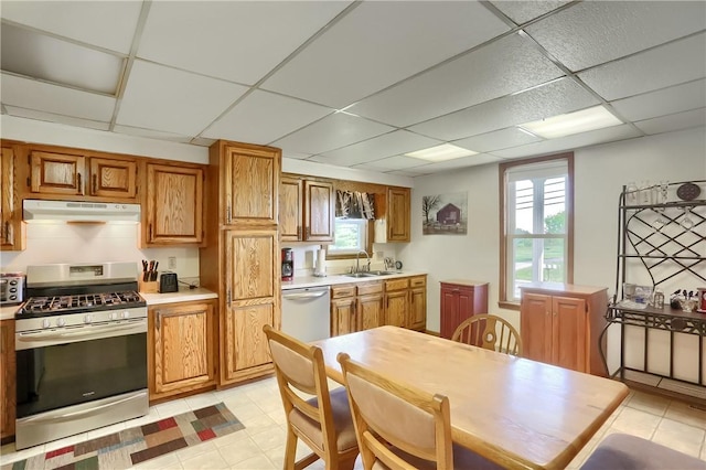 kitchen featuring appliances with stainless steel finishes, light tile patterned floors, a drop ceiling, and sink