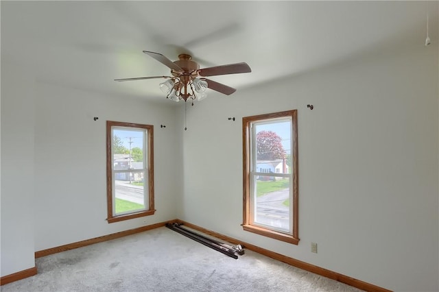 carpeted empty room with a wealth of natural light and ceiling fan