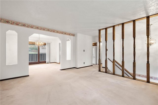 carpeted spare room featuring a textured ceiling and a chandelier