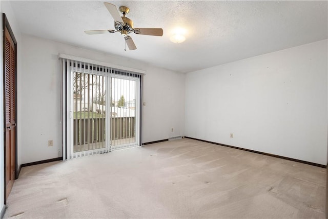 unfurnished room with ceiling fan, a textured ceiling, and light carpet