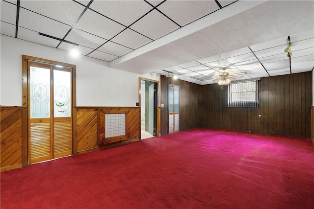 basement with ceiling fan, wooden walls, and carpet floors