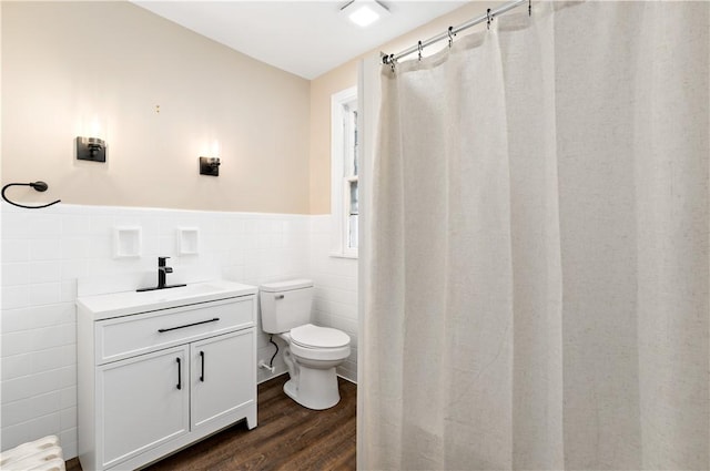 bathroom featuring wood-type flooring, vanity, toilet, and tile walls