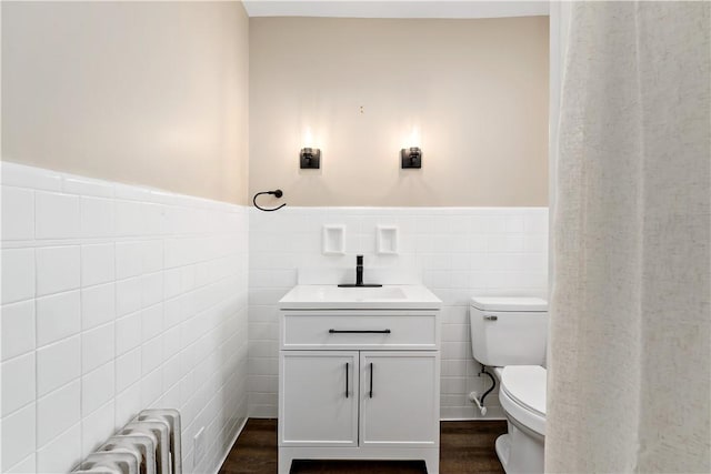 bathroom featuring hardwood / wood-style floors, toilet, tile walls, and radiator