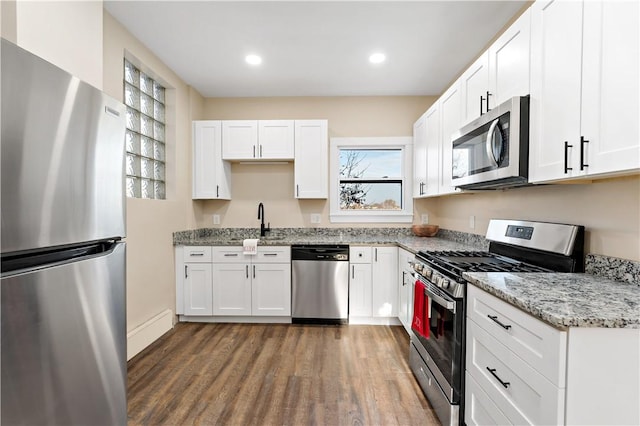 kitchen featuring white cabinets, sink, dark hardwood / wood-style floors, light stone countertops, and stainless steel appliances