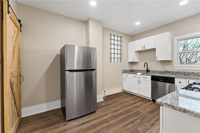 kitchen featuring plenty of natural light, a barn door, light stone counters, and stainless steel appliances