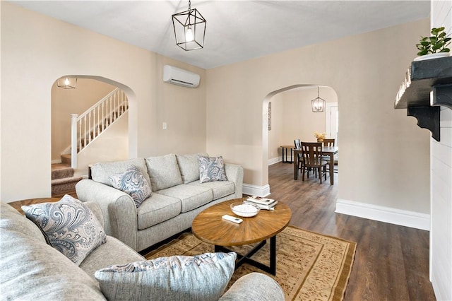 living room featuring an inviting chandelier, dark hardwood / wood-style floors, and a wall unit AC