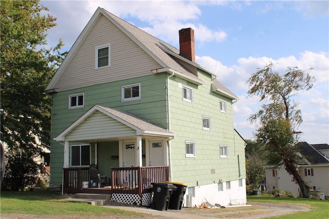 rear view of house featuring a lawn and covered porch