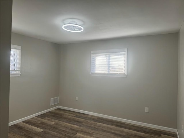 empty room with dark hardwood / wood-style floors and a wealth of natural light