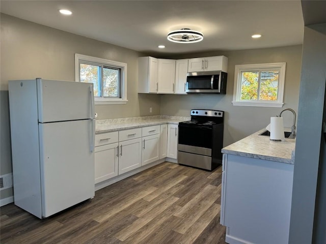 kitchen with dark hardwood / wood-style flooring, sink, white cabinetry, and stainless steel appliances