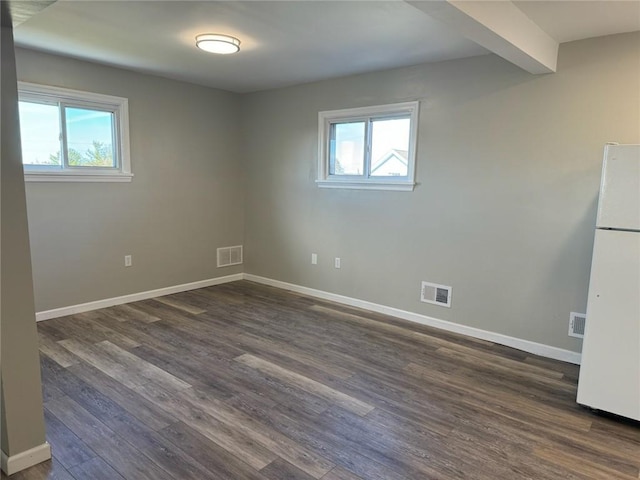 spare room featuring beam ceiling and dark hardwood / wood-style floors