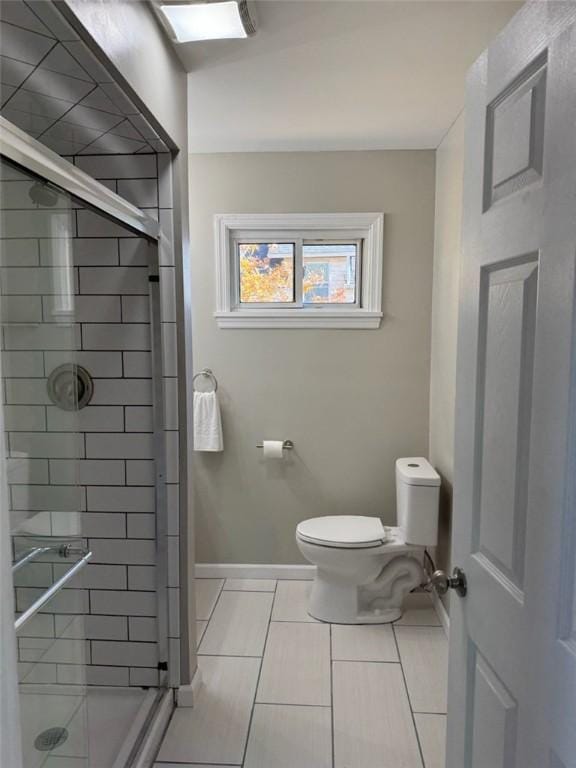 bathroom featuring tile patterned flooring, toilet, and a shower with shower door