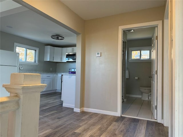 kitchen with white cabinets, dark hardwood / wood-style floors, and white fridge