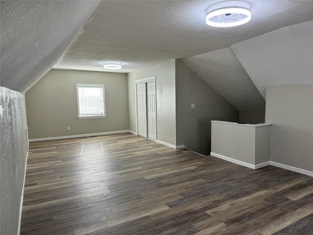 bonus room with dark hardwood / wood-style flooring, lofted ceiling, and a textured ceiling