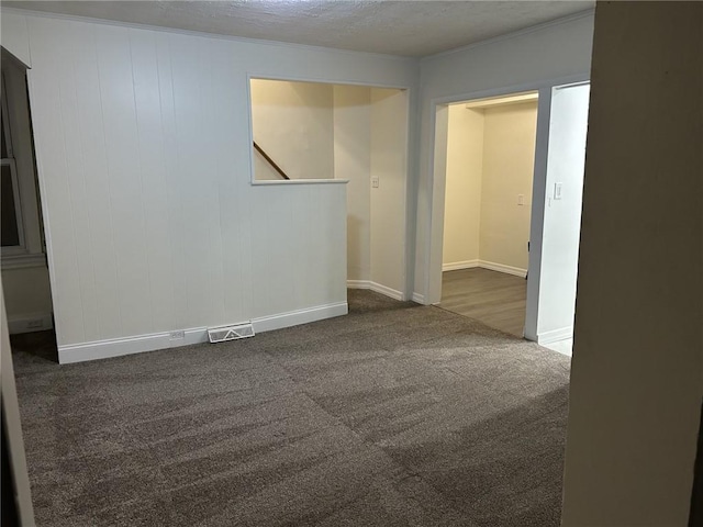 spare room featuring dark carpet and a textured ceiling