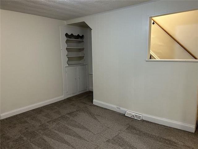 empty room with dark carpet and a textured ceiling