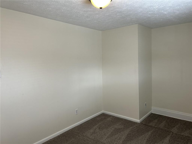 empty room with dark colored carpet and a textured ceiling