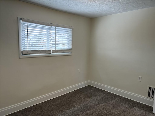 empty room with a textured ceiling and carpet floors