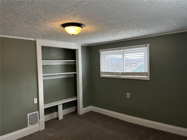 unfurnished bedroom featuring dark colored carpet, ornamental molding, and a textured ceiling