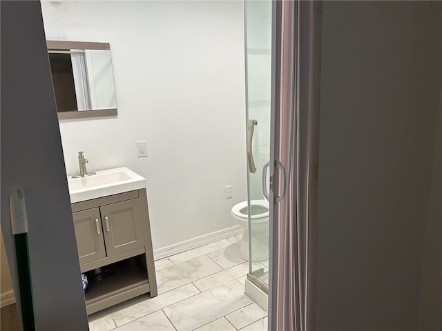 bathroom featuring vanity, toilet, and a shower with shower door