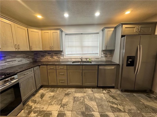 kitchen featuring sink, backsplash, dark stone countertops, a textured ceiling, and appliances with stainless steel finishes