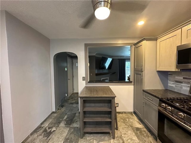 kitchen with backsplash, ceiling fan, stainless steel appliances, and a textured ceiling