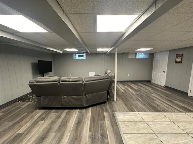 living room featuring hardwood / wood-style floors, a drop ceiling, and wood walls